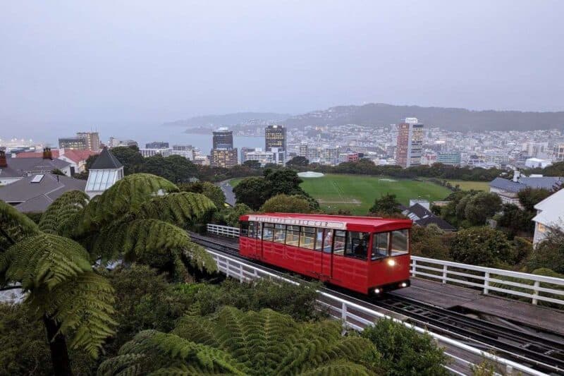 Ein Wagen der feuerroten Standseilbahn vor dem Stadtpanorama von Wellington