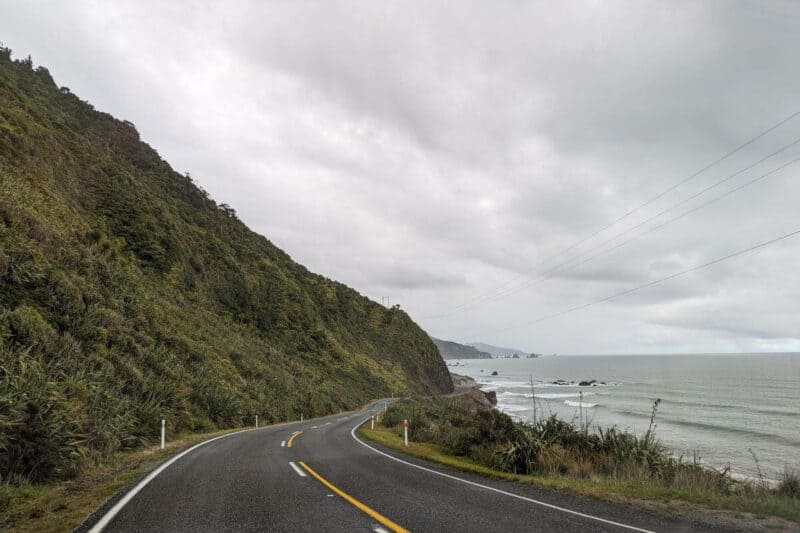Der State Highway 6 an der neuseeländischen Westküste mit Bergen links und Meer rechts ist eine wichtige Verbindungsstraße auf einem Roadtrip durch Neuseeland