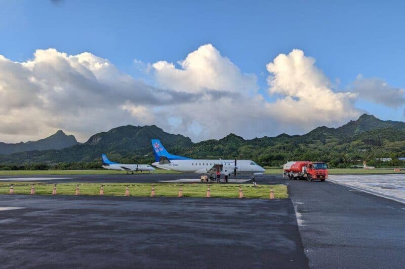 Flugzeuge auf dem Fluhafen in Rarotonga vor den grün bewaldeten Bergen der Insel