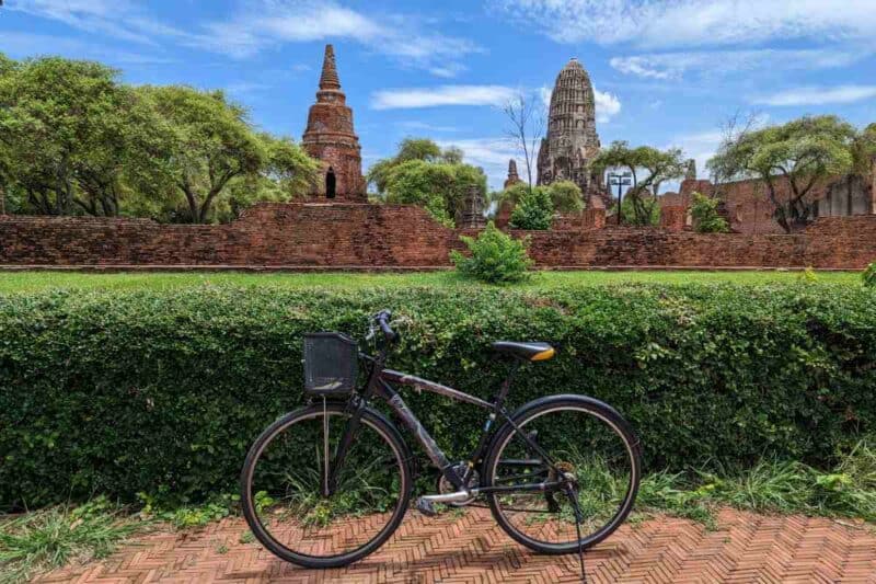 Türme und Parkanlage des Wat Mahathat mit Fahrrad im Vordergrund