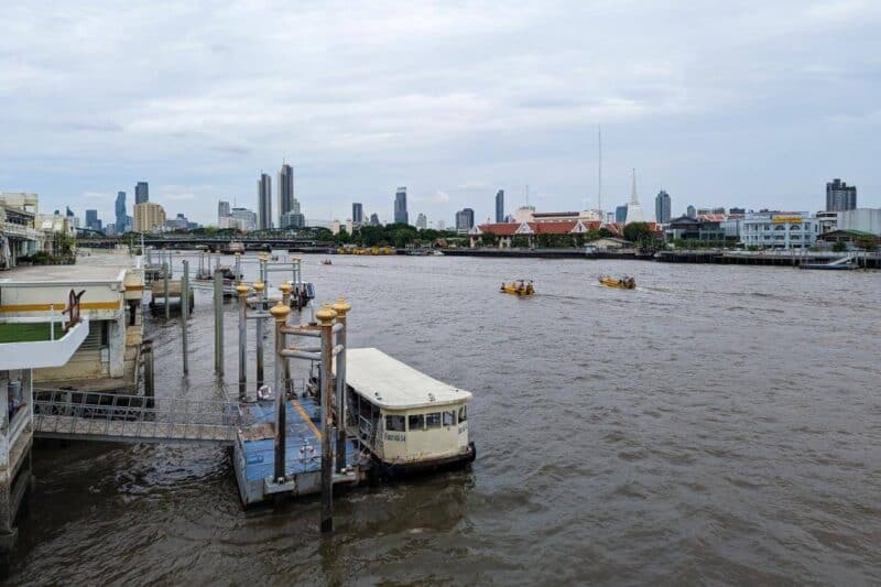 Boote auf dem Chao Phraya in Bangkok mit Wolkenkratzern im Hintergrund
