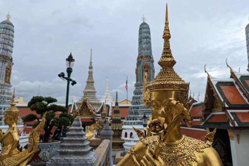 Goldene Statue mit Türmen im Hintergrund im Grand Palace in Bangkok
