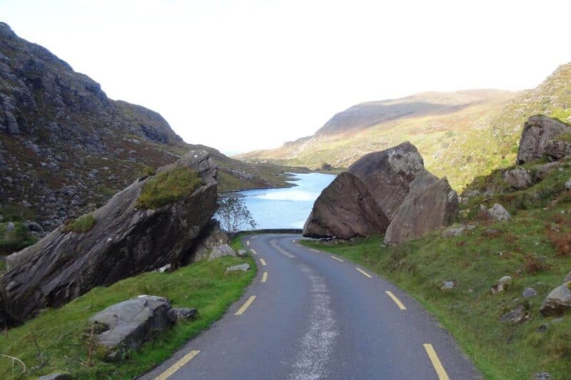 Die enge Passstraße des Gap of Dunloe führt zwischen zwei Felsen hindurch, im Hintergrund ein See