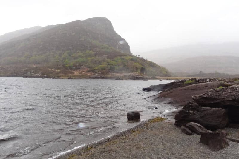 Kiesstrand an einem See im Killarney National Park bei starkem Regen