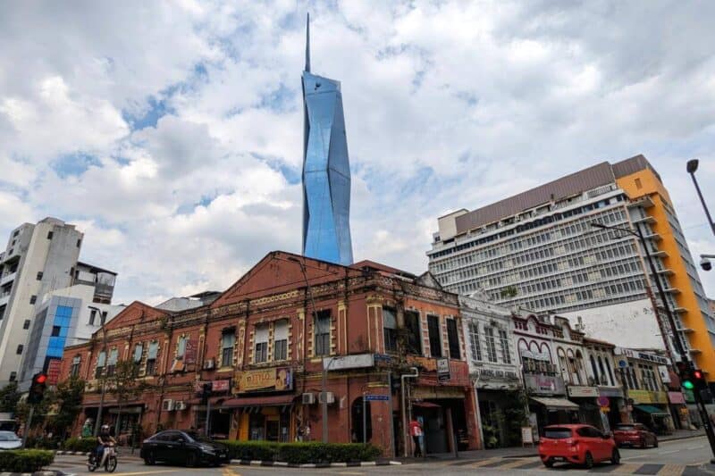 Einstöckige Ziegelhäuser vor der modernen Glasfassade des Wolkenkratzers Merdeka 118 in Kuala Lumpur