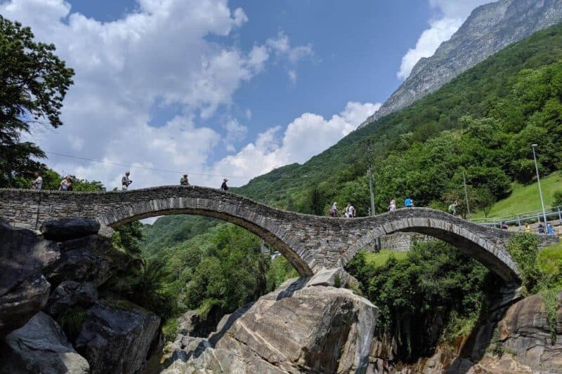 Die zweibogige Fußgängerbrücke Ponte dei Salti vor dem Gebirge im Hintergrund