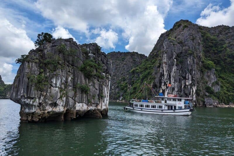 Ein Ausflugsboot fährt zwischen den schroffen Felsen in der Halong-Bucht in Vietnam