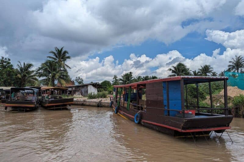 Überdachte Holzboote ankern am Ufer des Mekong in Vietnam