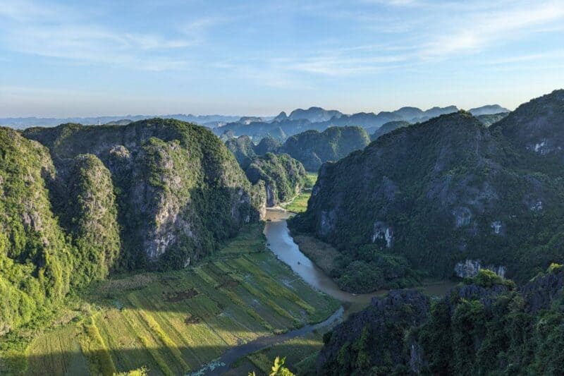 Blick von den Bergen der Mua Caves auf die Felsnadeln und einen Fluss in der Region Tam Coc