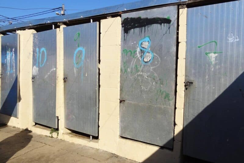 Metalltüren mit aufgesprühten Nummern in einem Waschhaus in Kayamandi