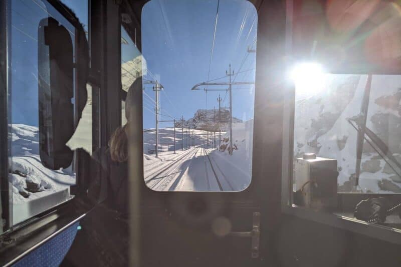 Blick auf die verschneiten Schienen der Gornergratbahn durch das Führerhaus